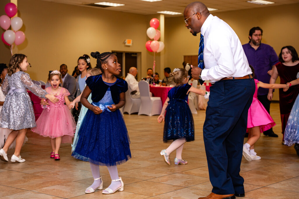 Father and daughter joyfully dancing at a special event, celebrating their bond.