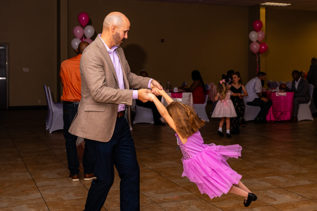 Father and daughter enjoying a joyful dance at a special event.