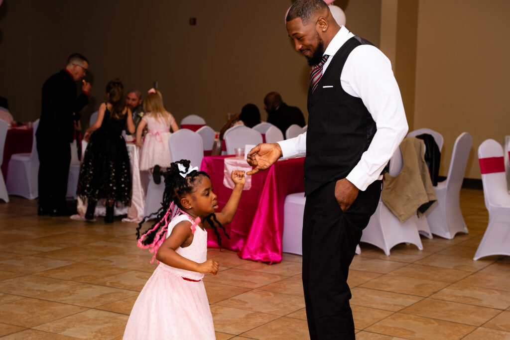 Father and daughter share a joyful moment dancing together at a special event.